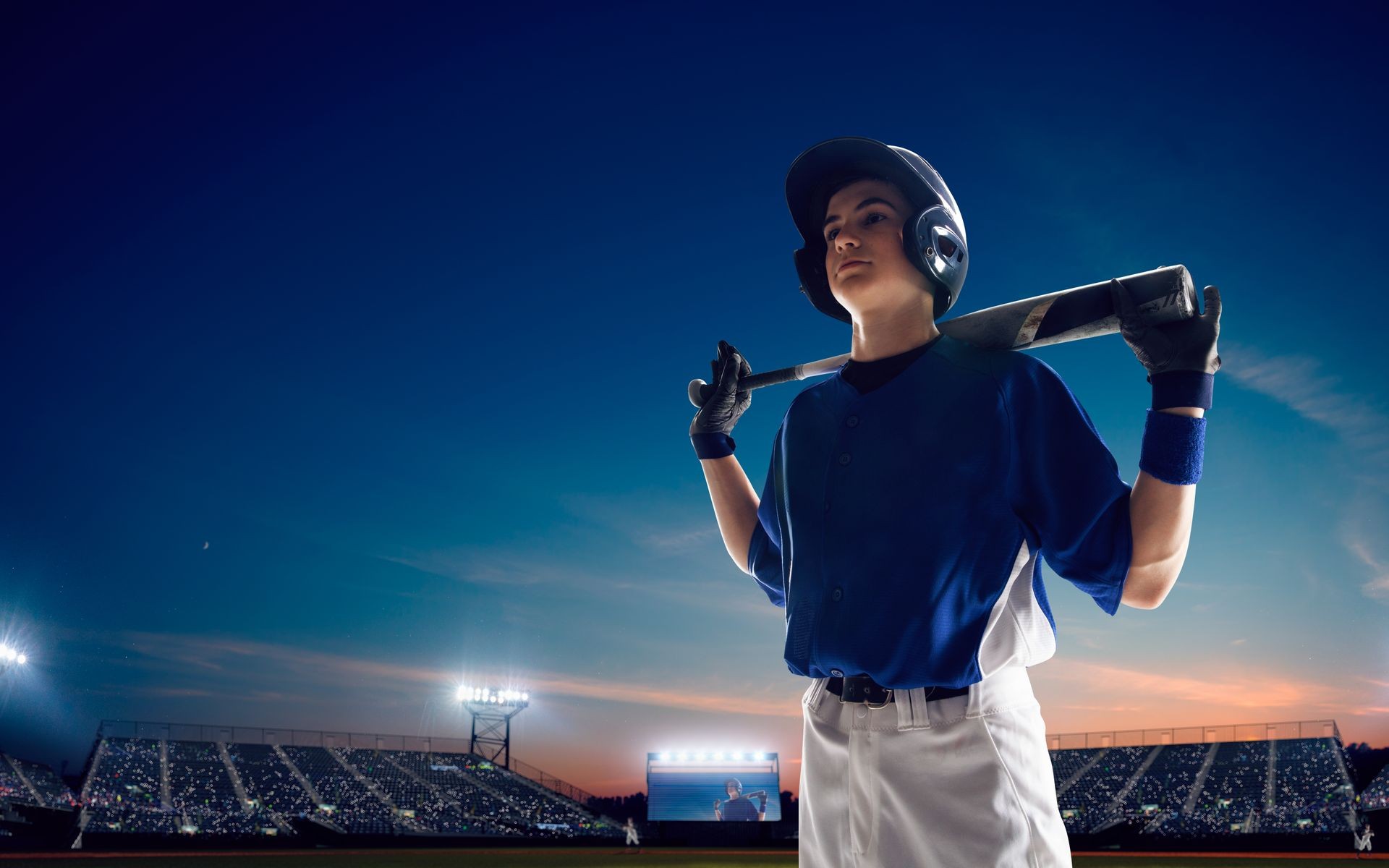 Baseball player at professional baseball stadium in evening during a game.